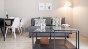 A modern living room with a glass coffee table, a sofa with cushions, a dining table with chairs, and a floor lamp. - Vacation Apartment 'Casa Weimar' with Private Terrace and Wi-Fi (Costa Calma)