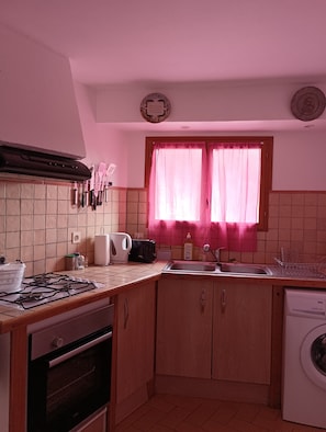 A compact kitchen with a gas stove, a toaster, a sink, and a washing machine.