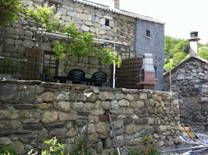 A stone building with a rustic exterior, a metal fence, and a chimney.