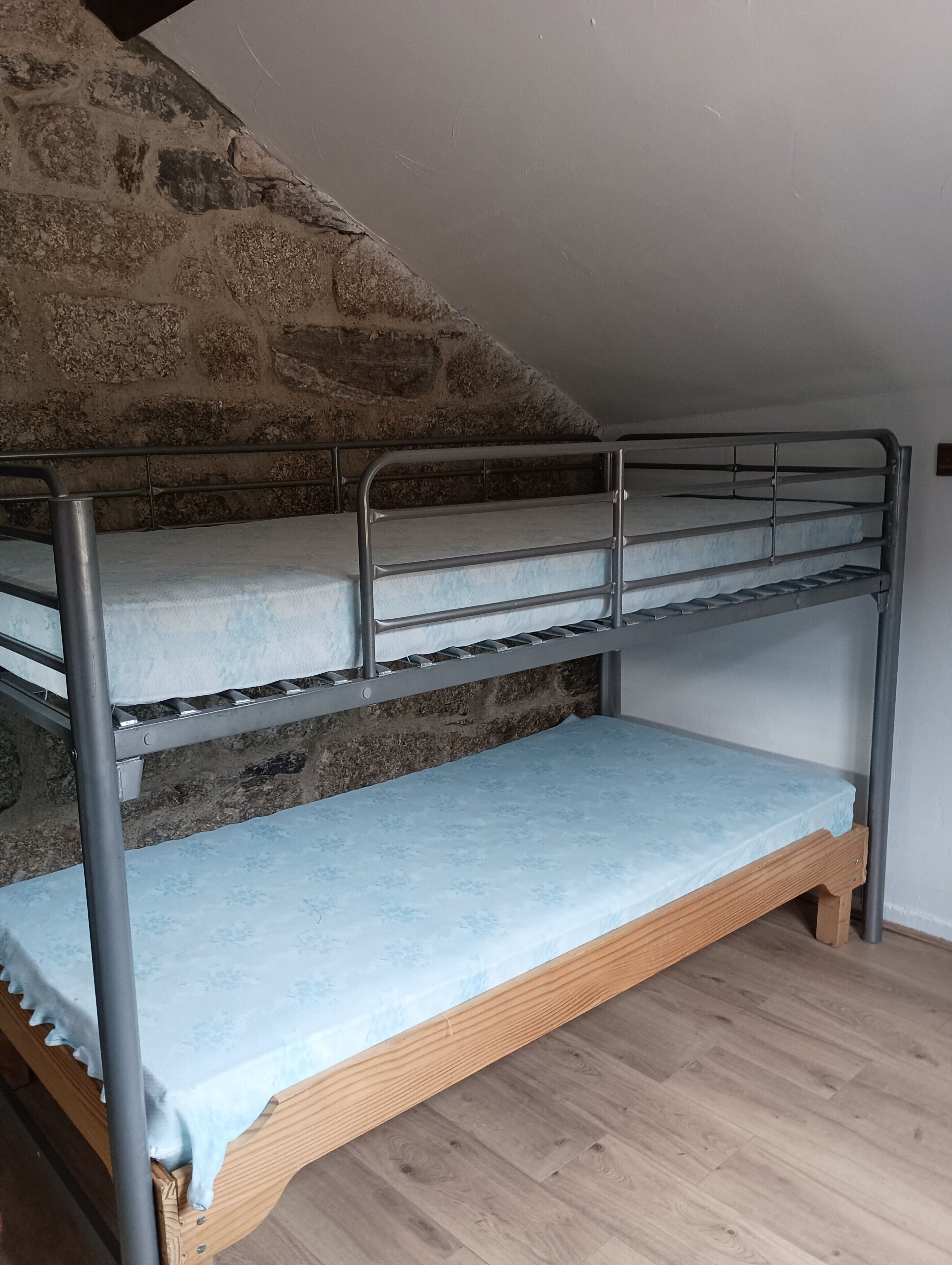 A bunk bed with a stone wall behind it.