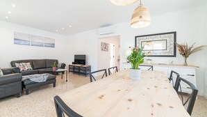 Un salon moderne avec une table à manger en bois, des canapés noirs et un téléviseur.