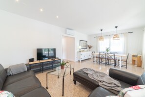 Un salon moderne avec un canapé, un téléviseur et un coin repas.