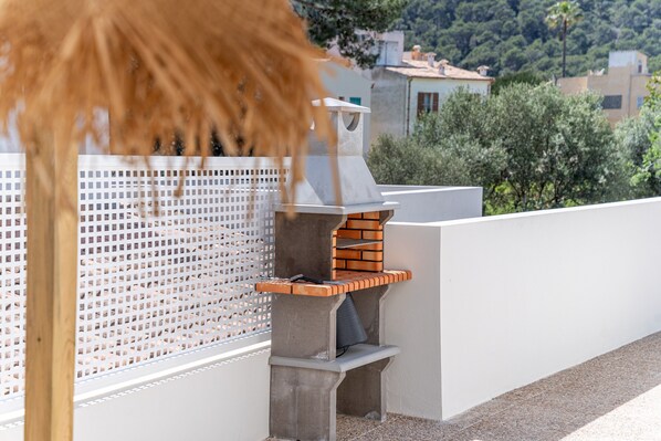 A rooftop with a brick oven and a white wall with a perforated design.