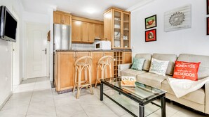 A modern kitchen with wooden cabinets, a stainless steel refrigerator, a microwave, and two bar stools. - Apartment 'Casa Molins' with Shared Pool, Private Terrace and Wi-Fi (Dénia)