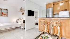 A modern kitchen with wooden cabinets, a refrigerator, and a dining area with two wicker chairs. - Apartment 'Casa Molins' with Shared Pool, Private Terrace and Wi-Fi (Dénia)
