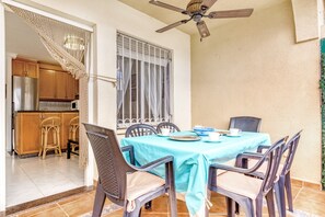 A dining area with a table set for four, a ceiling fan, and a kitchen visible through an open door. - Apartment 'Casa Molins' with Shared Pool, Private Terrace and Wi-Fi (Dénia)