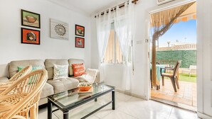 A living room with a sofa, a glass coffee table, wicker chairs, and a dining area with a table and chairs. - Apartment 'Casa Molins' with Shared Pool, Private Terrace and Wi-Fi (Dénia)