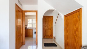 Un corridoio con porte in legno, una zona cucina e una lavanderia.