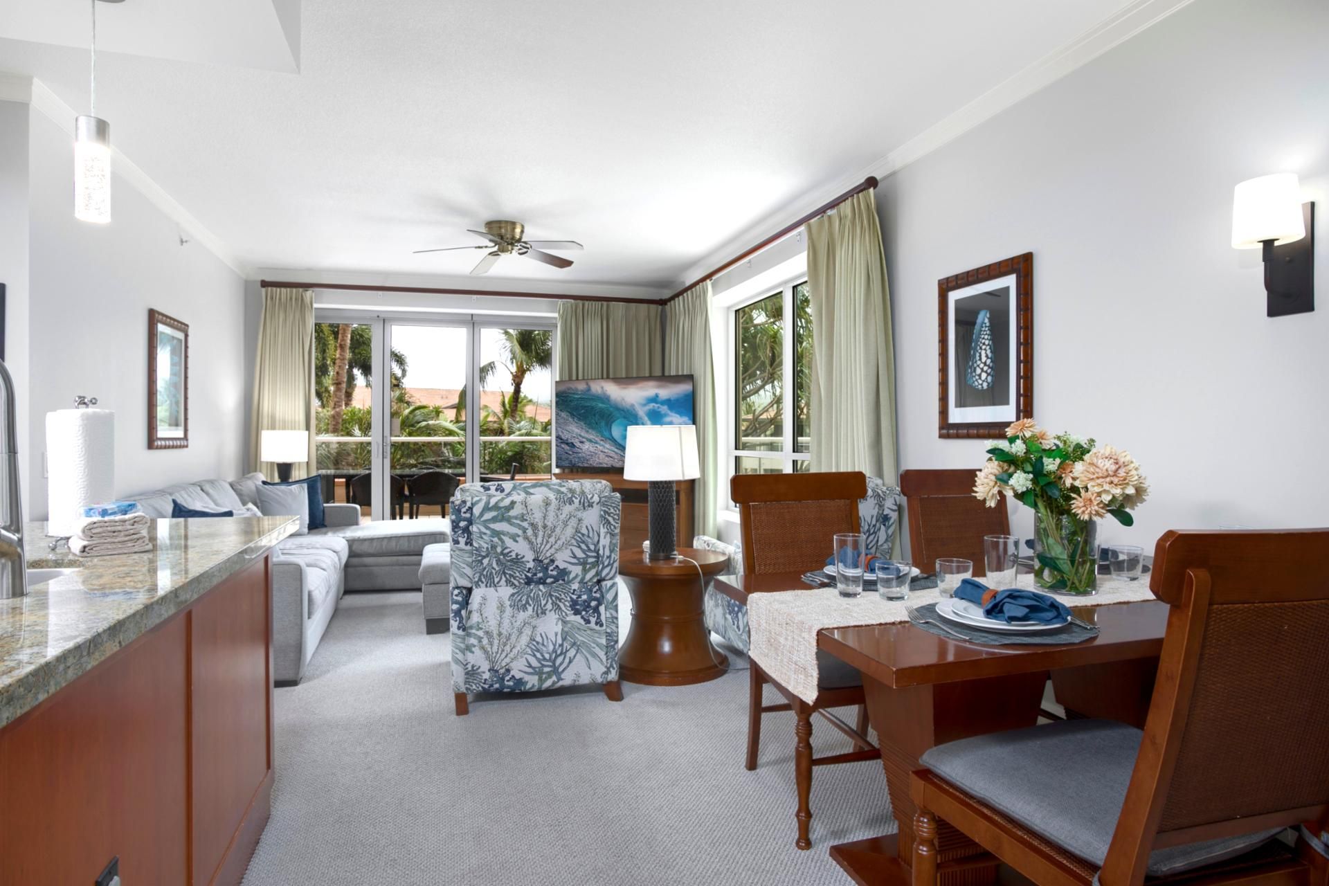 Une chambre d’hôtel comprenant un coin repas, un canapé, un fauteuil, une table dressée pour deux personnes et un tableau accroché au mur.