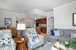 A living room with a sofa, armchair, and a coffee table with a bottle and glass.