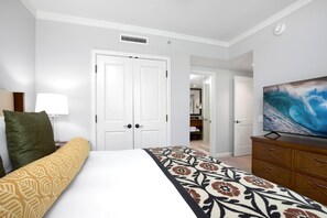 Ein Hotelzimmer mit Bett, Fernseher, Kommode und einer Tür zu einem Badezimmer.