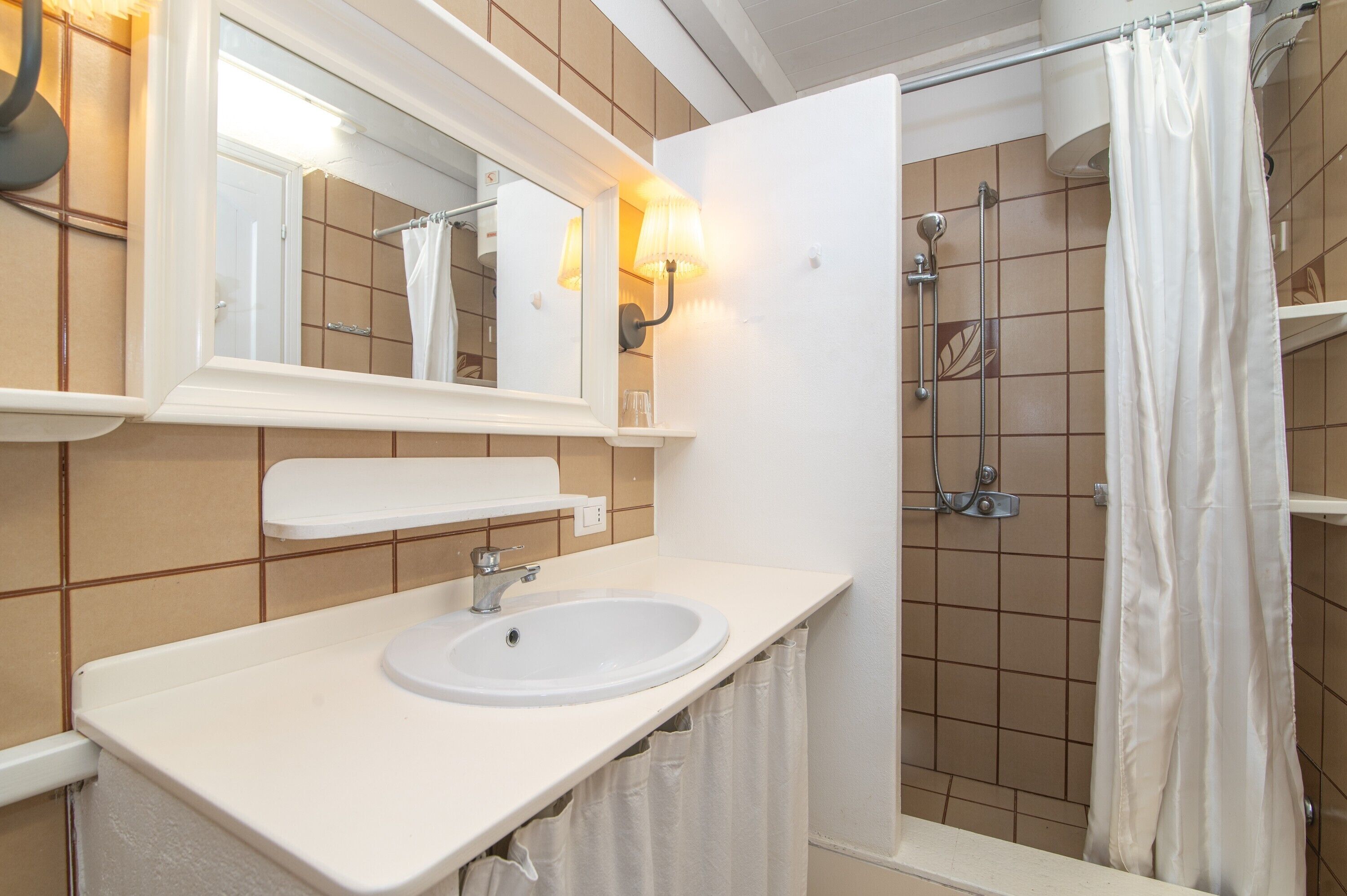 Un baño con lavamanos blanco, espejo y cortina de ducha.