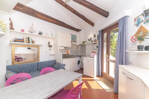 Une cuisine compacte équipée d’un lave-linge, un coin repas avec une table et des chaises, et un grand miroir.