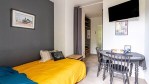 A bedroom with a bed, a desk, a chair, a TV, and a bookshelf. - Cottage 'Les Gîtes Du Robelier - L'étang' with Private Terrace, Shared Garden and Wi-Fi (Bouaye)