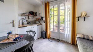 A compact kitchen with a dining table, a microwave, and a trash bin. - Cottage 'Les Gîtes Du Robelier - L'étang' with Private Terrace, Shared Garden and Wi-Fi (Bouaye)