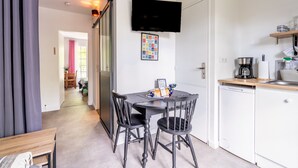A compact kitchen with a dining table, chairs, a TV, and a coffee maker. - Cottage 'Les Gîtes Du Robelier - L'étang' with Private Terrace, Shared Garden and Wi-Fi (Bouaye)