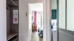 A hallway leading to a bedroom with a bed, a chair, and a window. - Cottage 'Les Gîtes Du Robelier - L'étang' with Private Terrace, Shared Garden and Wi-Fi (Bouaye)