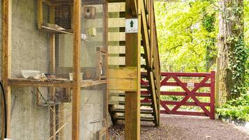 Une structure en bois agrémentée d’une volière métallique, d’une porte rouge et d’une enseigne indiquant « Le Nid ».