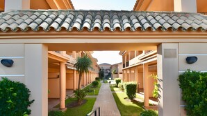Un pasillo con techo de azulejos, columnas y vegetación.
