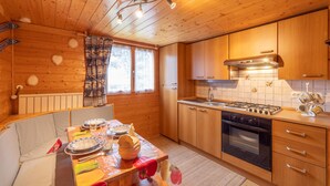 L’intérieur d’une cabane en bois comprend un coin repas, une cuisine et une grande fenêtre.