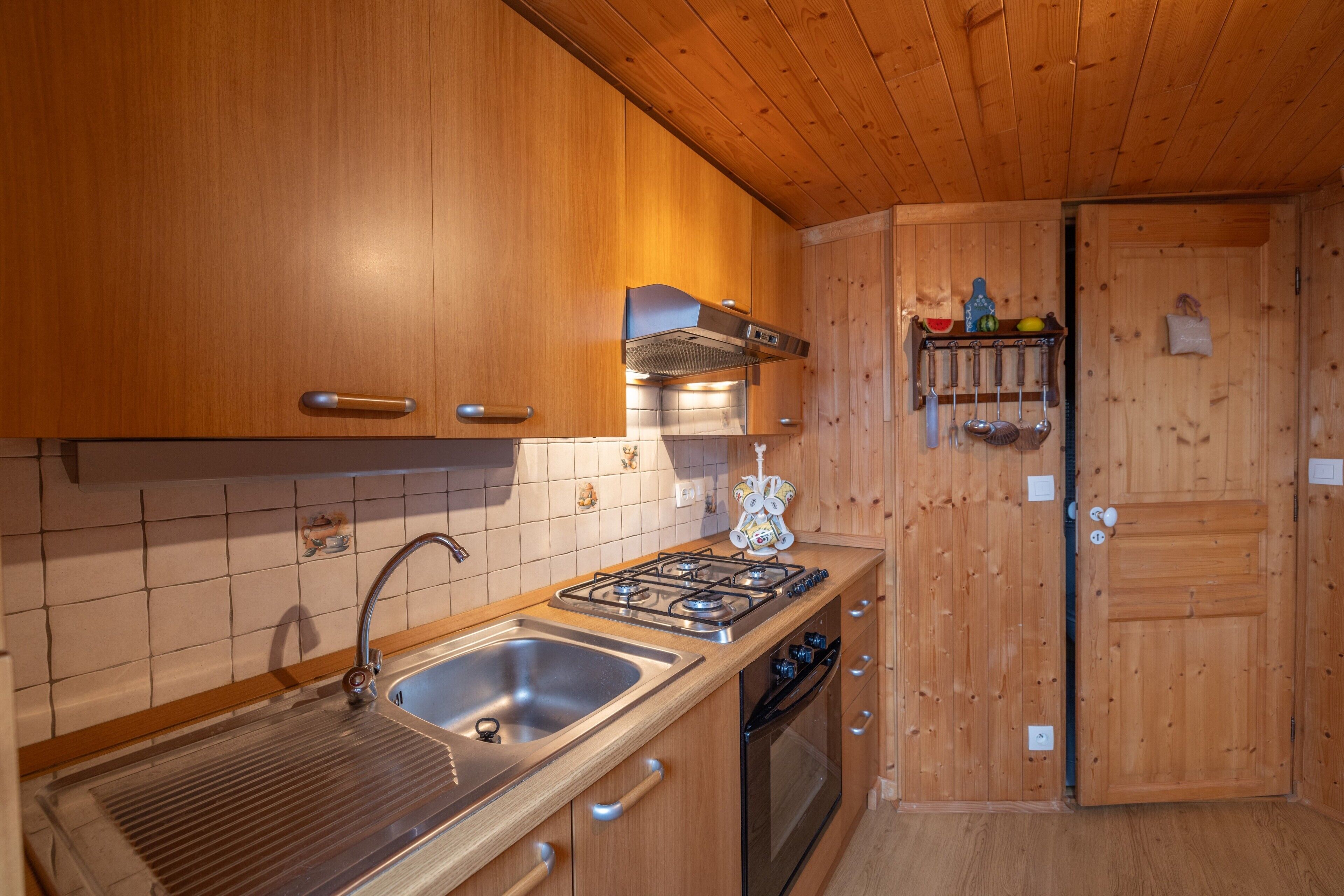 A kitchen with wooden cabinets, a stainless steel sink, a gas stove, and a built-in oven.