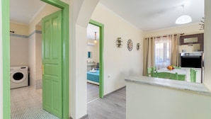A kitchen with a dining area, a green door, and a washing machine in the background.
