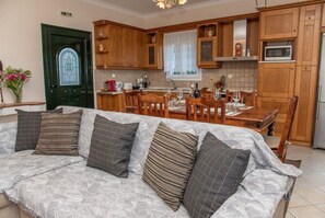 Una sala de estar con sofá, armarios de madera, una mesa de comedor y una zona de cocina.