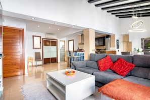 A modern living room with a grey sofa, a white coffee table, and a wooden door. - Apartment 'Somni' with Sea View, Wi-Fi and Air Conditioning (Xàbia)