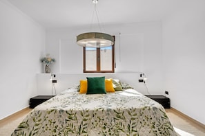 A bedroom with a bed, a window, a wall-mounted light fixture, and a small table. - Apartment 'Somni' with Sea View, Wi-Fi and Air Conditioning (Xàbia)