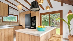 Une cuisine moderne avec des meubles en bois, un îlot en marbre et une grande fenêtre.