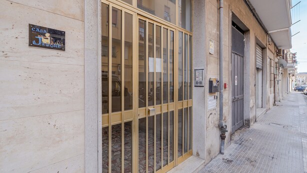 Fachada de edificio con un amplio escaparate de vidrio, un letrero que dice 'CASA JERONE' y un piso de baldosas.