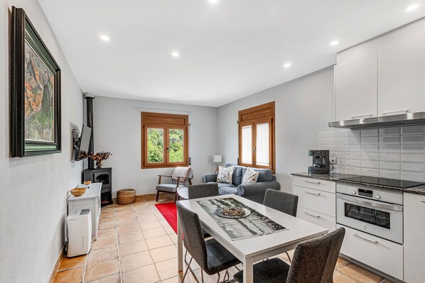 A compact kitchen with a dining area, a sofa, and a fireplace.