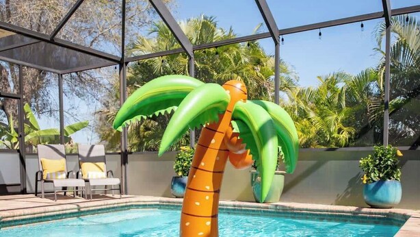 A pool with a floating palm tree and lounge chairs.