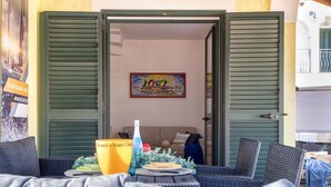 An open doorway leading to a room with a sofa and a table set with a bottle and glasses.