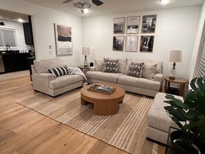 A living room with a sofa, a coffee table, and a side table. There are framed pictures on the wall. - Osage Oasis: Pool, Hot Tub, Near Downtown & Trails (Bentonville)