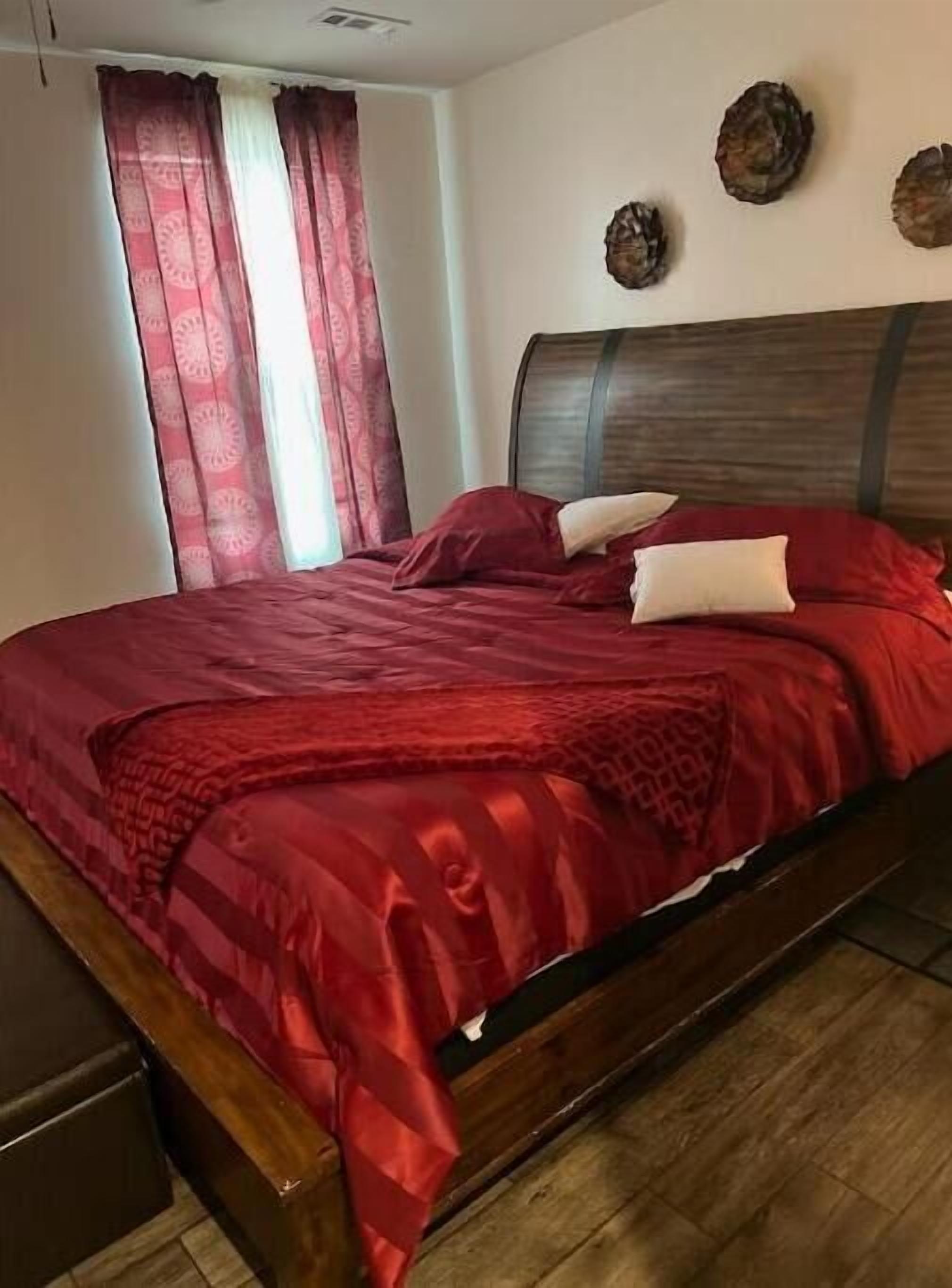Ein Bett mit Holzbettrahmen und einer roten Bettdecke.