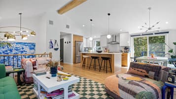 Un salon moderne avec un canapé, une table basse et une bibliothèque. Il y a également un coin cuisine avec une table à manger et des chaises.