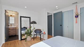 A modern bedroom with a bed, a desk, a chair, a potted plant, and a wardrobe.