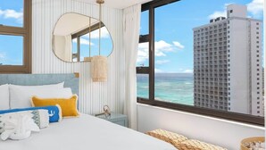 A hotel room with a bed, a large window with a city view, a round mirror, and a nightstand.