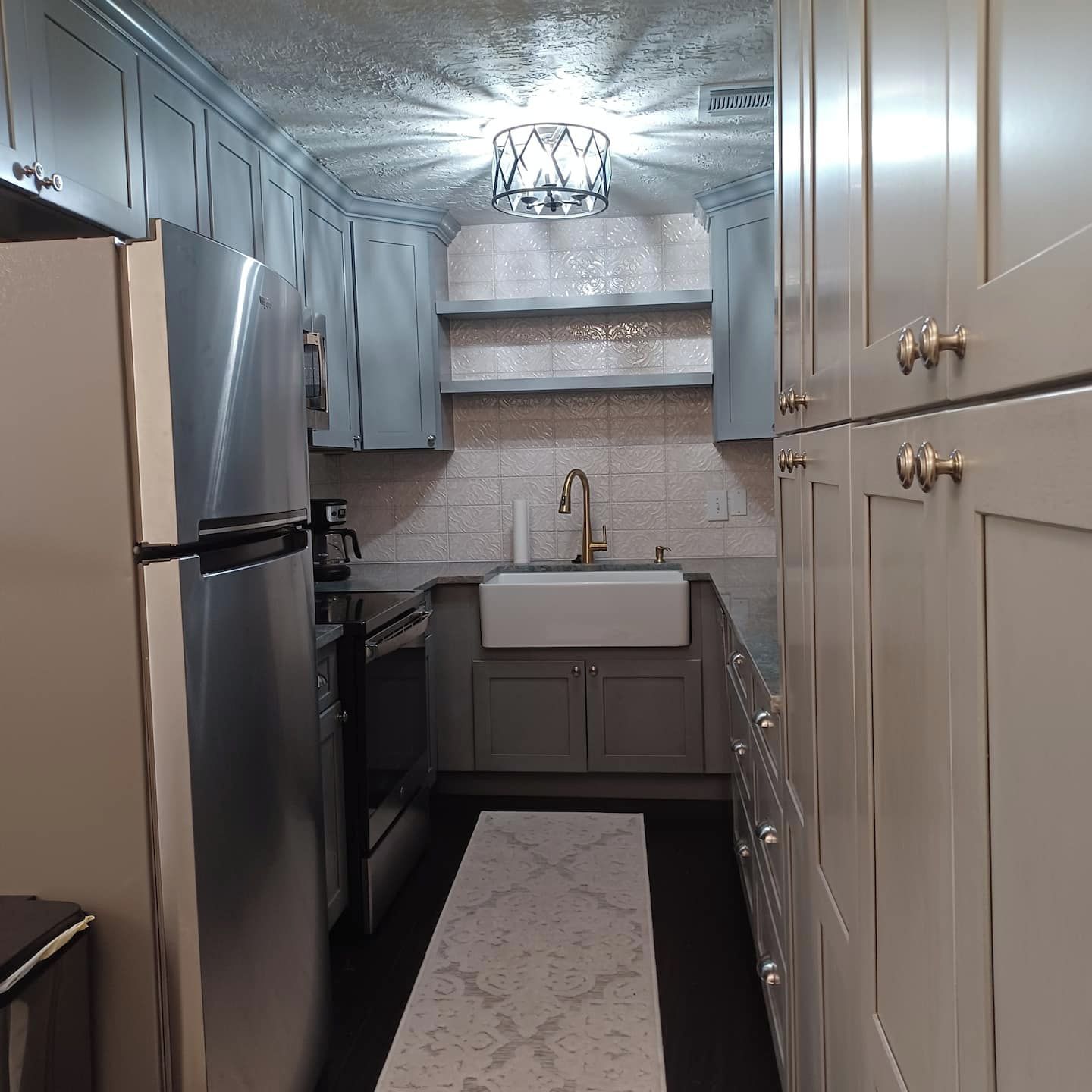 A compact kitchen with stainless steel appliances, a white sink, and light-colored cabinets.