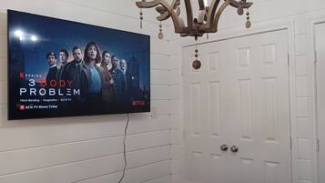 A bedroom with a television mounted on the wall, a chandelier, and a white door.