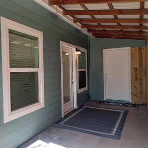 A covered porch with a door, a window, and a doormat.