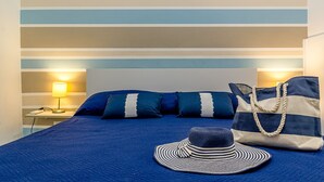 Un lit avec une couette bleue, des oreillers à rayures, un chapeau à rayures et un sac à rayures.