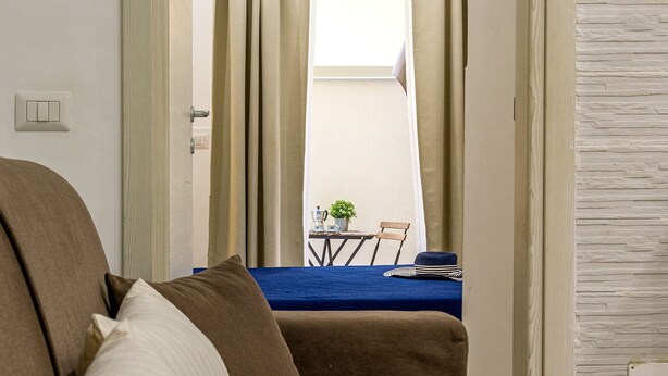 Une pièce comprenant un canapé, une table à manger avec des chaises, et une vue sur l’extérieur par une porte.