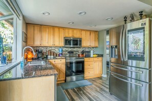 A modern kitchen with wooden cabinets, stainless steel appliances, and a large refrigerator.