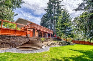 Eine Holzjagdhaus mit Veranda, umgeben von einer Steismauer und einem Rasen.