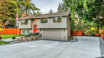 A two-story house with a garage, a front yard with a lawn, and a wooden fence.