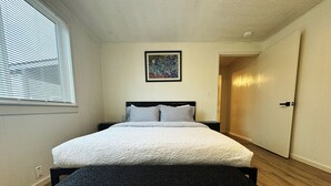 Une chambre à coucher avec un lit, un banc, un tableau et une porte.