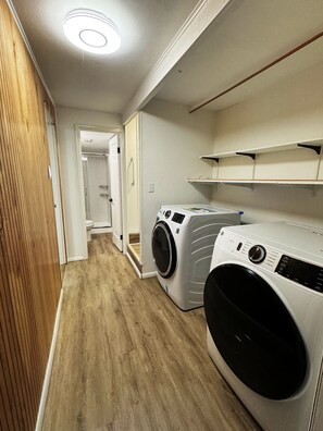 A laundry room with two front-loading washing machines, wooden flooring, and a white ceiling with recessed lighting. - Comfortable Coast Stay North Bend, Coos bay & Dunes (North Bend)