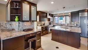 Una cocina moderna con armarios de madera oscura, encimeras de granito y electrodomésticos de acero inoxidable.